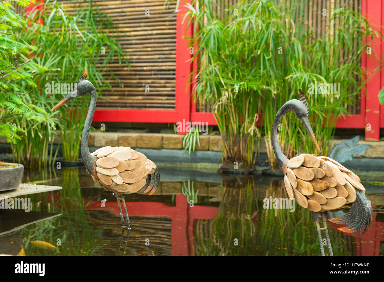 Cicogna metallica statue in piedi in acqua a una funzione in un cinese-giardino a tema in Edmonton, Alberta Foto Stock