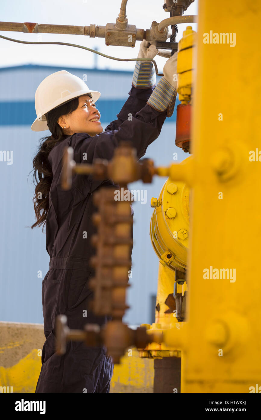 Potere femminile ingegnere Controllo tubo del combustibile i sensori in corrispondenza di impianto di alimentazione Foto Stock