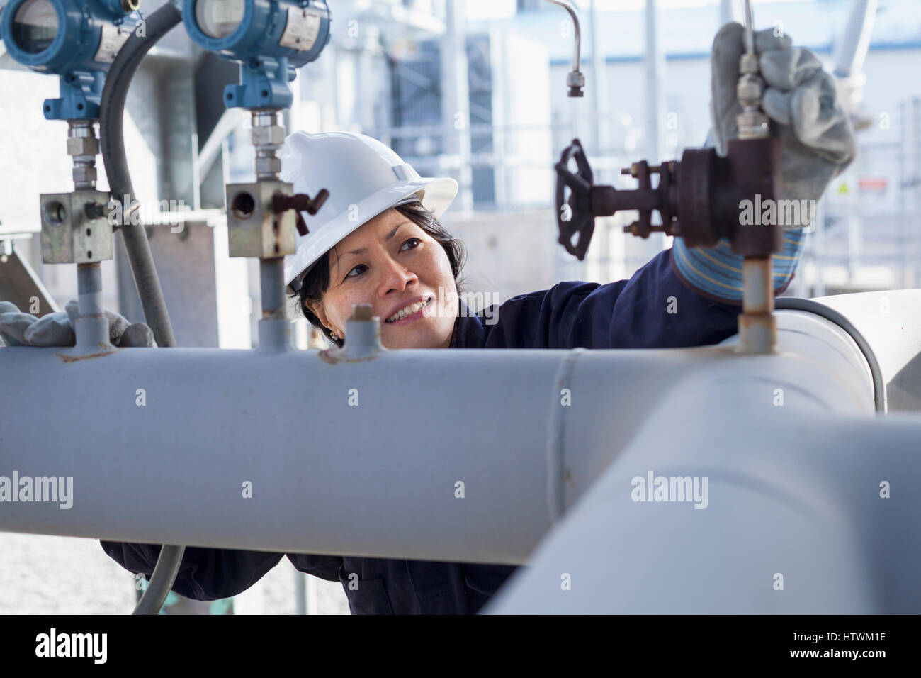 Femmina ingegnere di potenza controllando i trasduttori di pressione di impianto di alimentazione Foto Stock