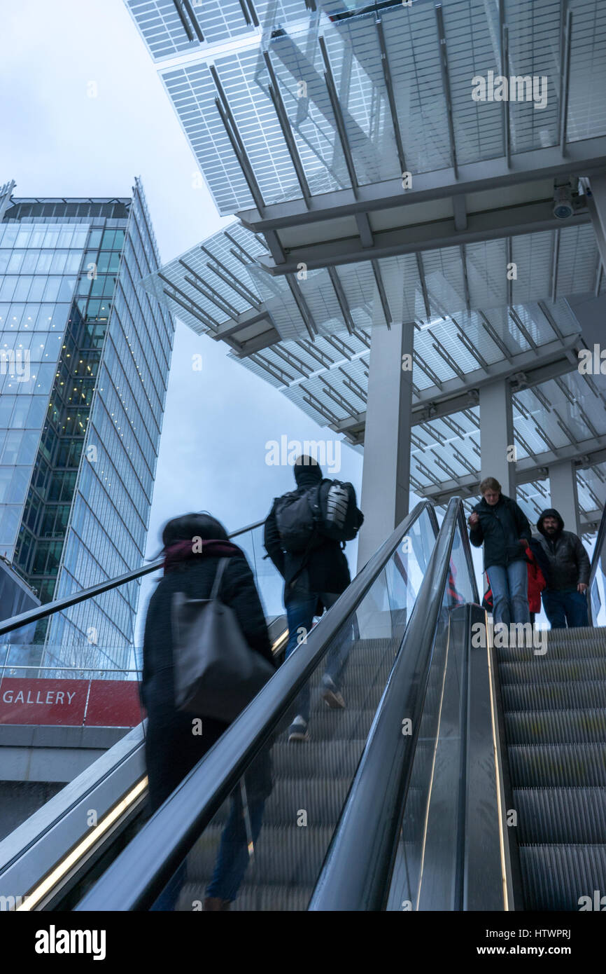 La gente viaggia su una scala mobile in un edificio moderno all'aperto a Londra Foto Stock