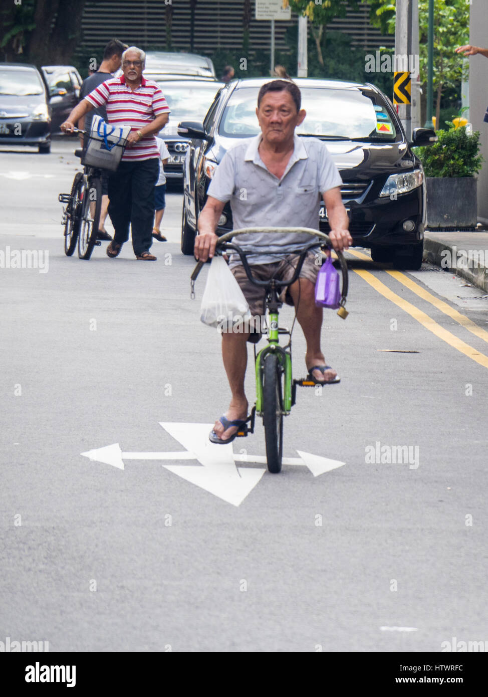 Pedone e ciclismo il traffico su una strada nella zona suburbana di Singapore. Foto Stock