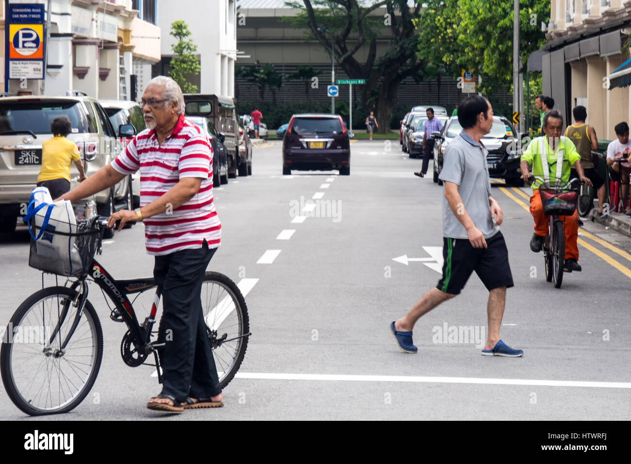 Pedone e ciclismo il traffico su una strada nella zona suburbana di Singapore. Foto Stock