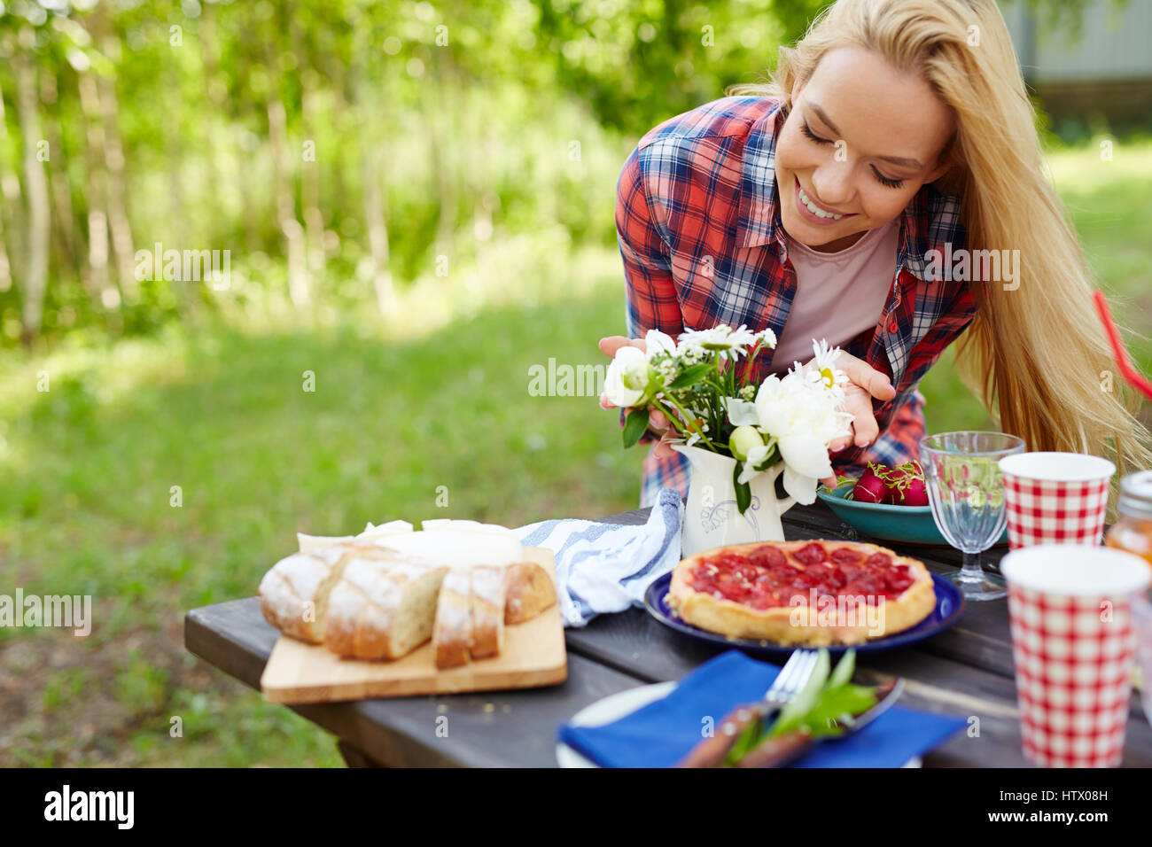 Giovane donna godendo di profumo di fiori sul tavolo serviti Foto Stock