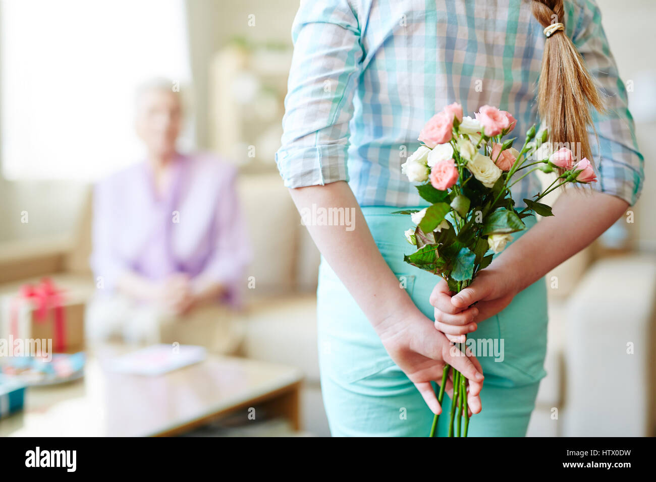 Ragazza con rose bouquet per la nonna dietro la schiena Foto Stock