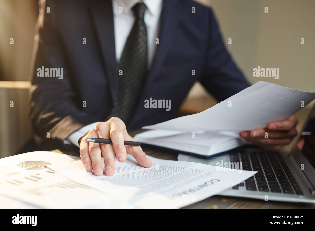 Closeup ritratto di un irriconoscibile imprenditore di successo vestita di nero abito formale Revisione finanze statistiche e documenti del contratto alla scrivania Foto Stock