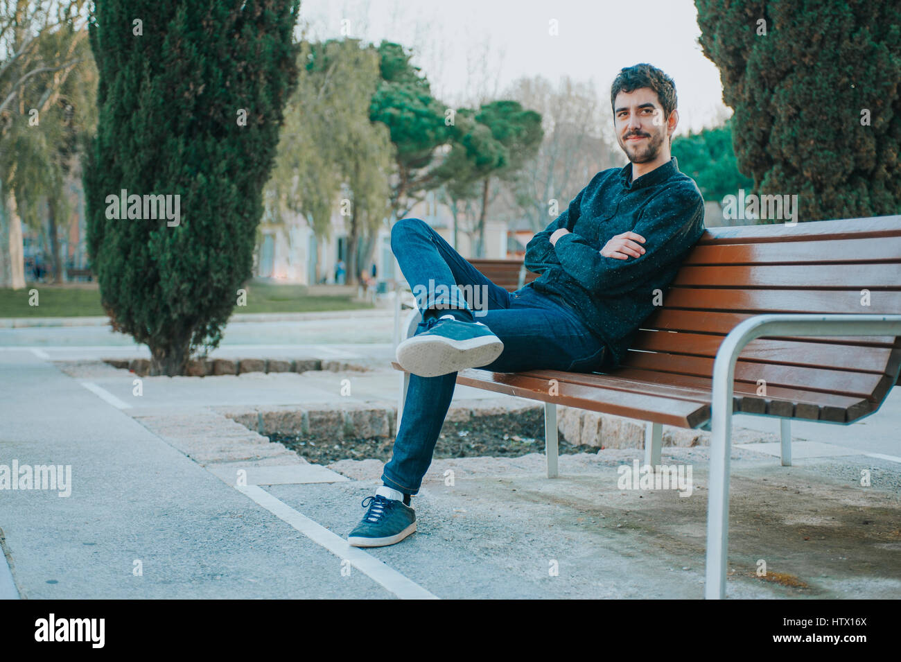 Giovane messicano uomo seduto in una panchina nel parco Foto Stock