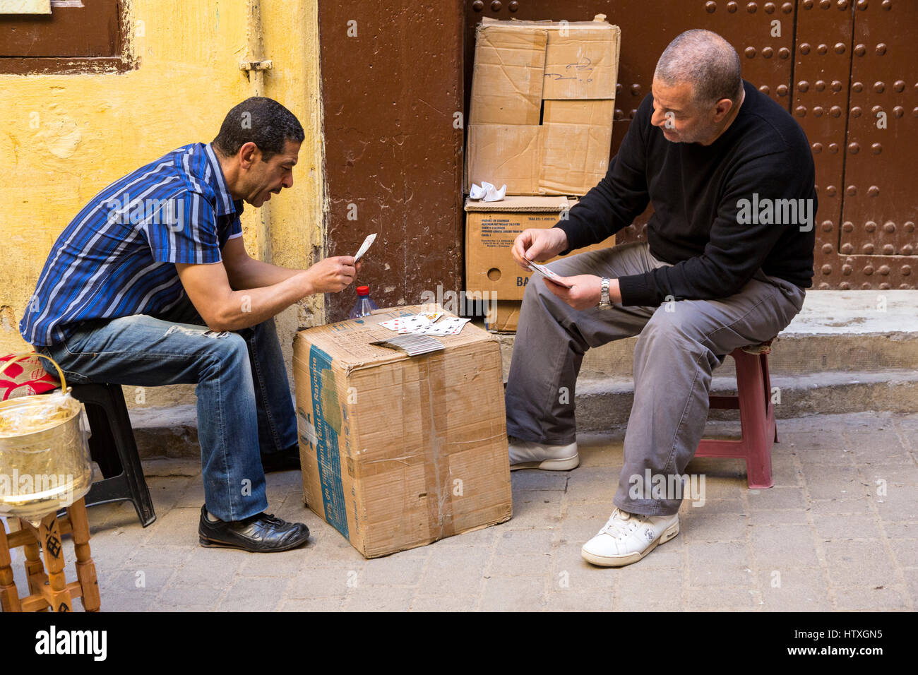 Fes, Marocco. Gli uomini le carte da gioco in una strada nella Medina. Foto Stock