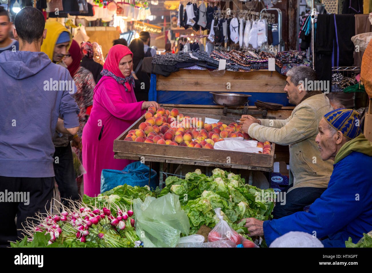 Fes, Marocco. Donna esaminando le pesche in Tala'a Kabira Street Market, Fes El-Bali. Foto Stock