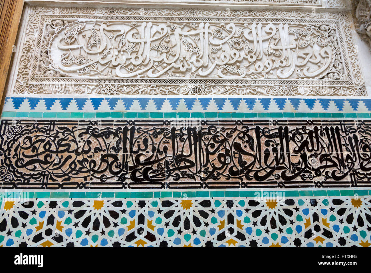 Fes, Marocco. Medersa Attarine, 14th. Secolo, Fes El-Bali. La calligrafia Araba in stucco e piastrella, geometrica delle piastrelle al di sotto. Foto Stock