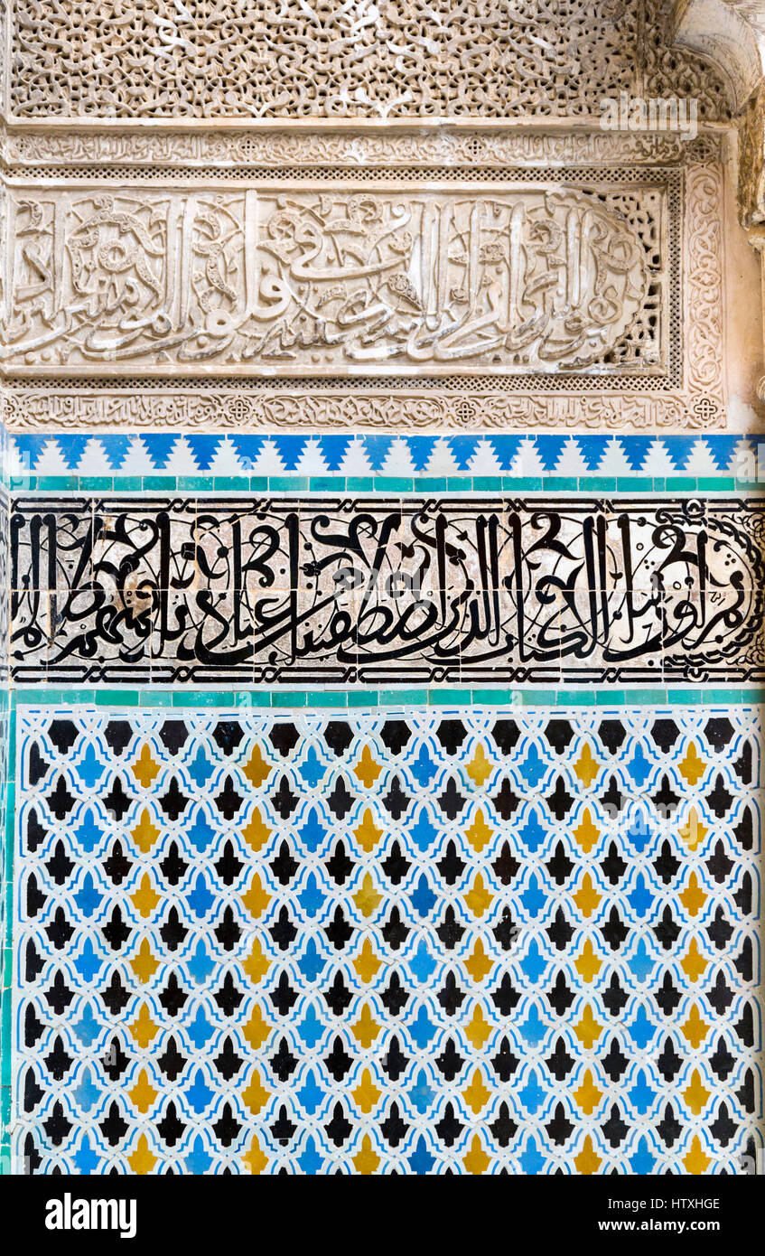 Fes, Marocco. Medersa Attarine, 14th. Secolo. Piastrelle decorative di lavorare sotto la calligrafia Araba su piastrelle, sotto la calligrafia su stucco. Foto Stock