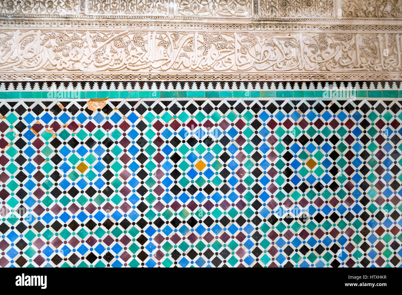 Fes, Marocco. Medersa Attarine, 14th. Secolo. La calligrafia Araba in stucco, piastrelle decorative sottostanti. Foto Stock
