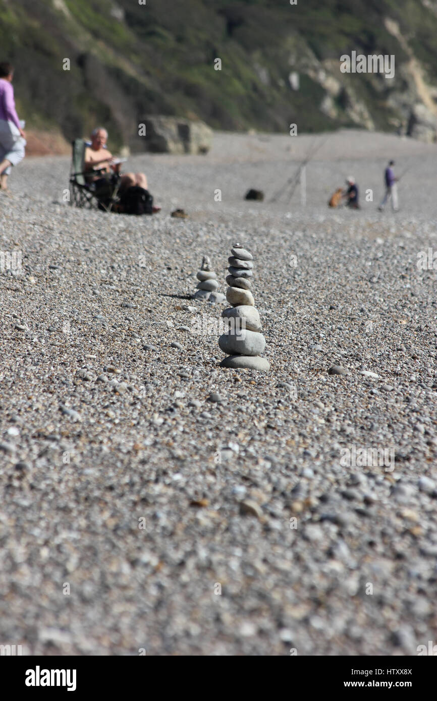 Un tumulo di ciottoli disposti sulla spiaggia di Branscombe, Devon, con un altro cairn di ciottoli disposti dietro in una giornata di sole Foto Stock