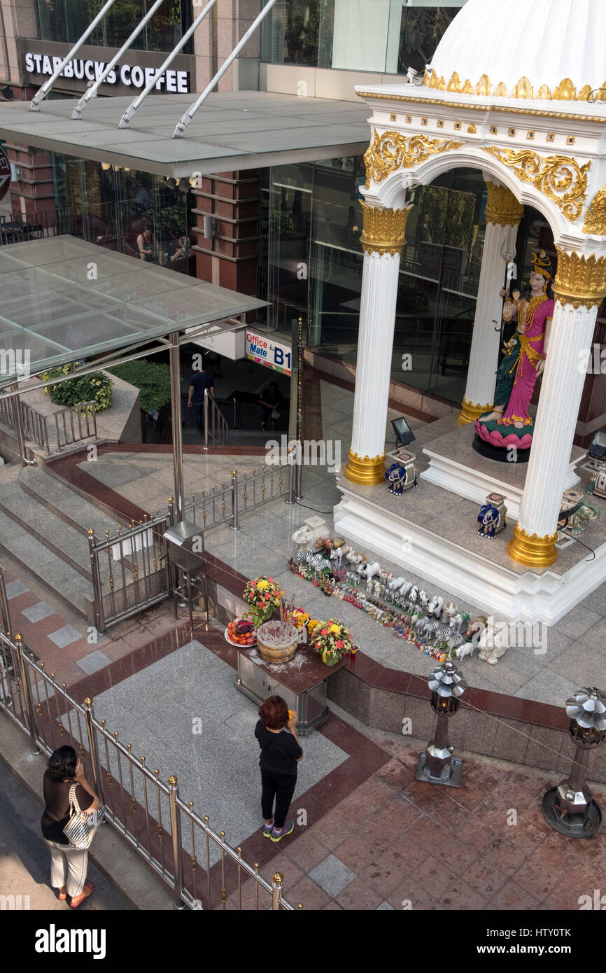 Le donne a pregare nel santuario accanto a Starbucks in Sukhumvit Road, Sukhumvit Bangkok, Thailandia Foto Stock
