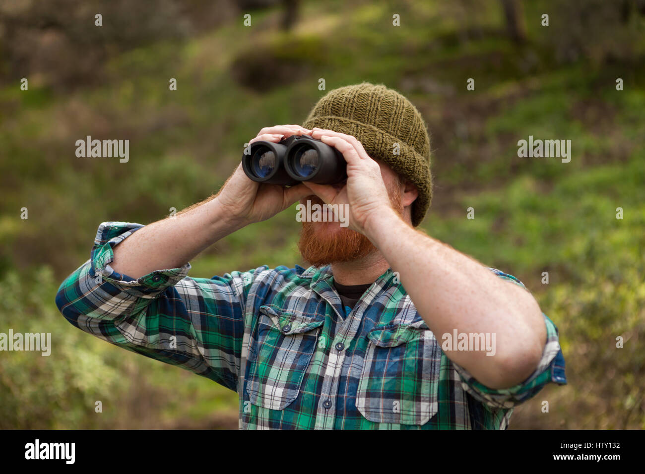 Dai capelli rossi uomo cercando di gettare un binocolo nel campo Foto Stock