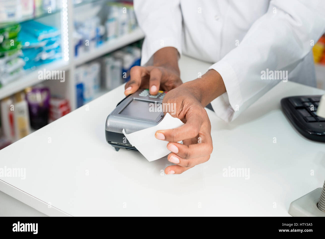 Il farmacista azienda ricevuta mentre si preme card reader del pulsante Foto Stock