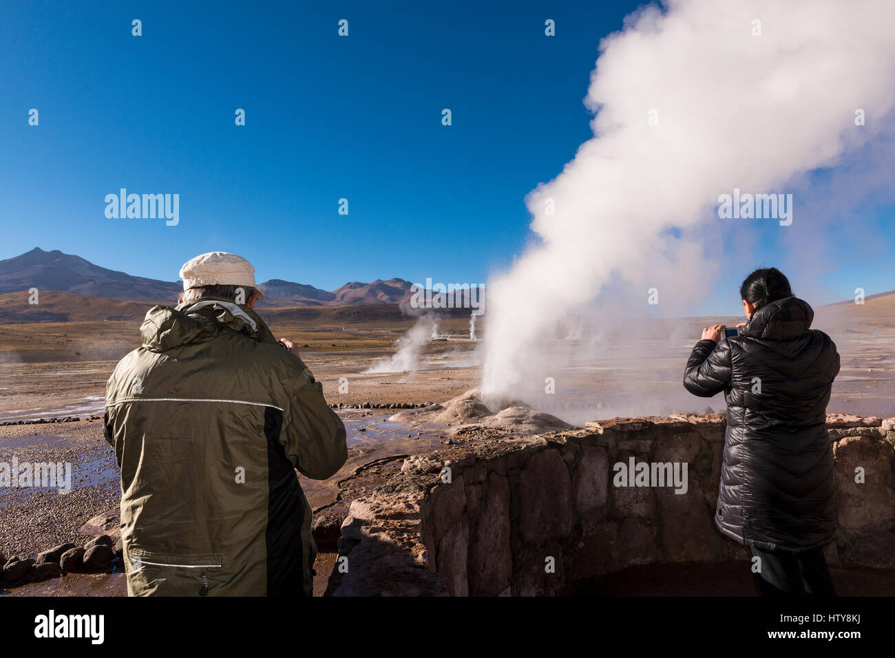 Geyser del Tatio, Cile - 24 Novembre 2013: turisti guardando un geyser nella geyser del Tatio campo nel deserto di Atacama, Cile settentrionale Foto Stock