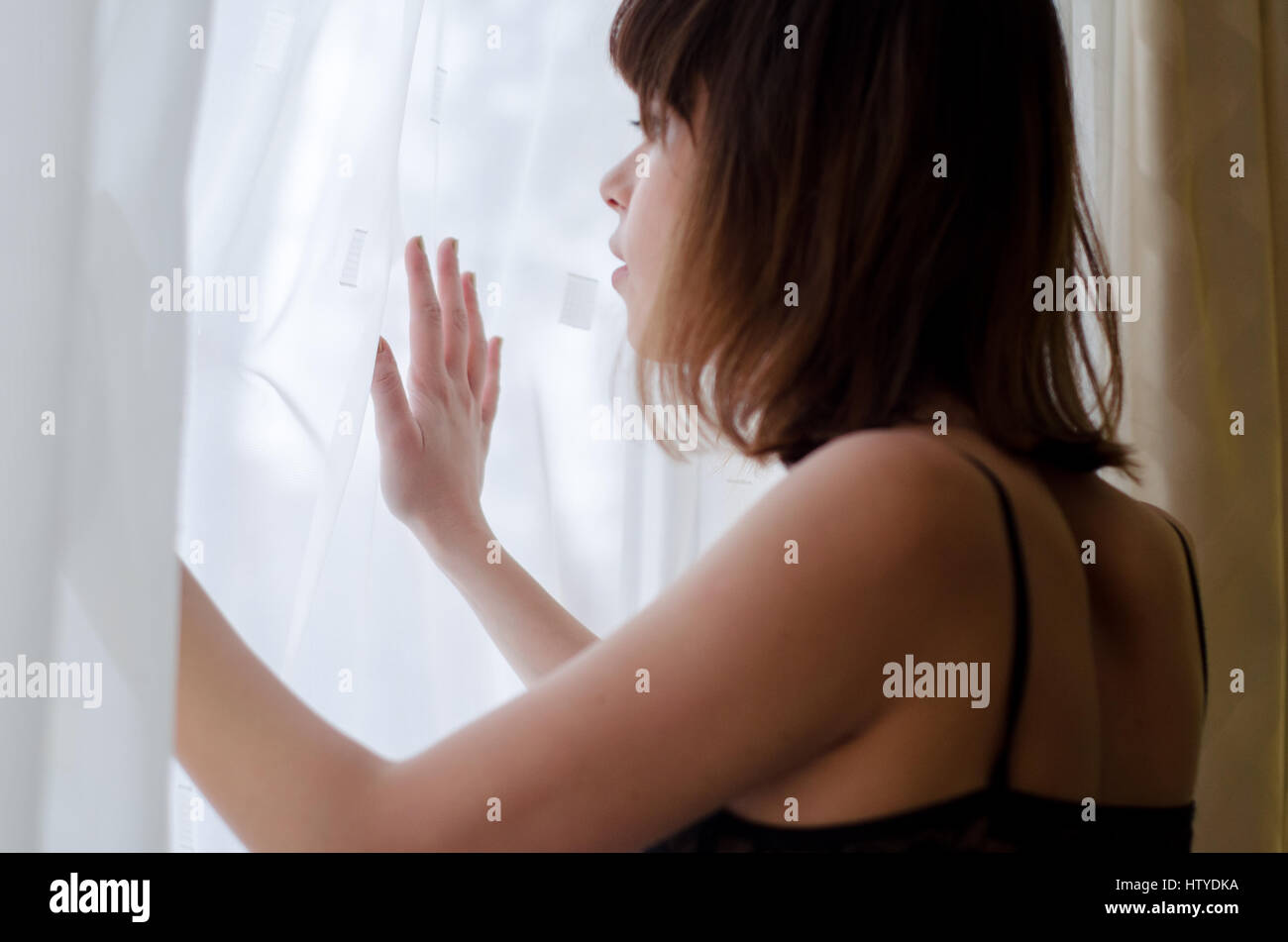 Donna che guarda fuori da una finestra Foto Stock