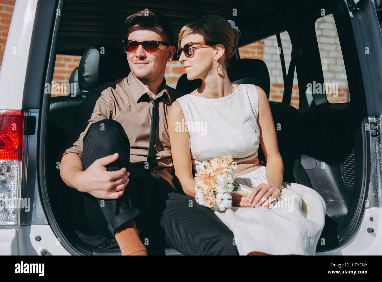 Giovane seduto nel bagagliaio di una vettura dopo il matrimonio Foto Stock