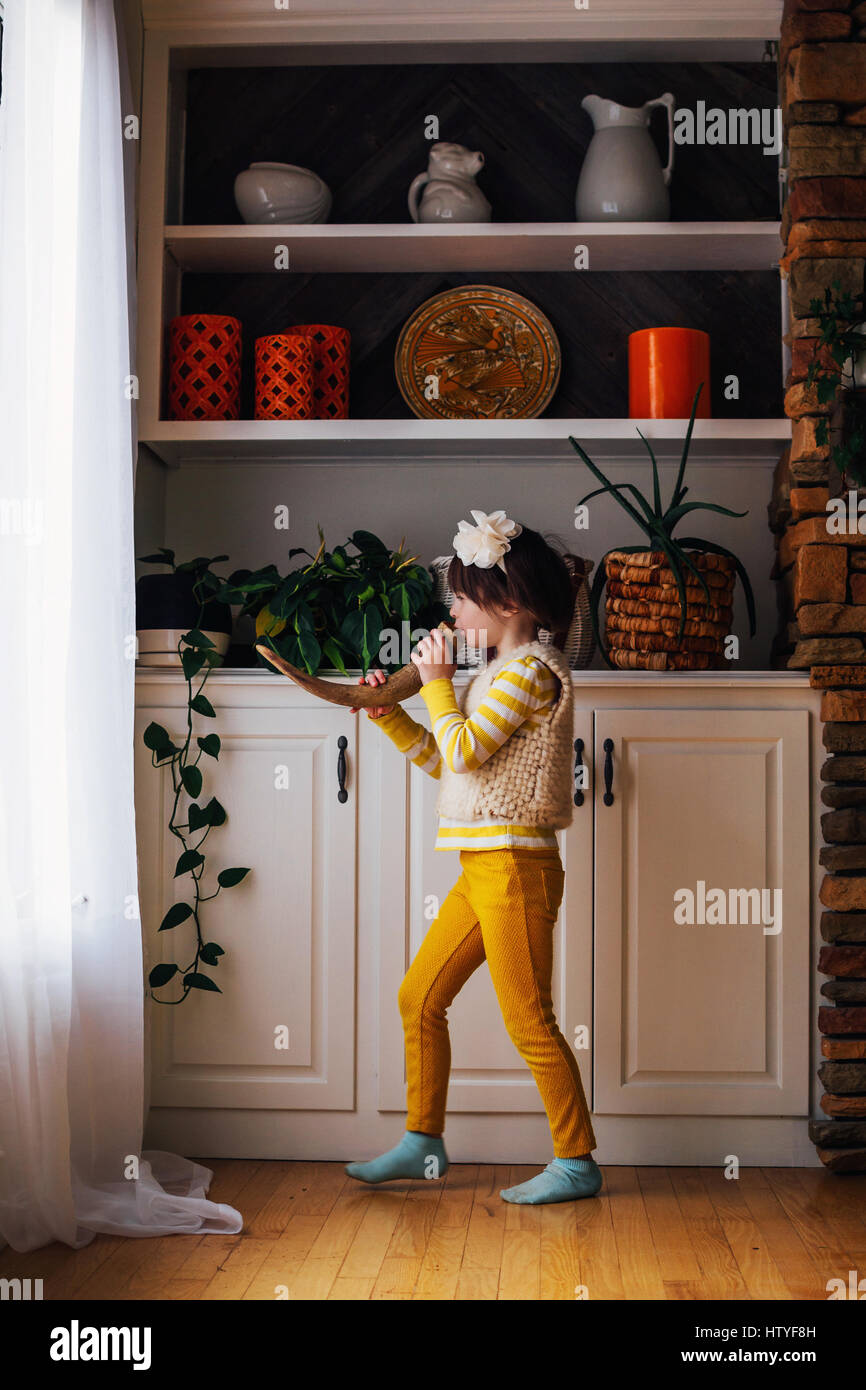 Ragazza in piedi di fronte alla finestra soffia un avvisatore acustico Foto Stock