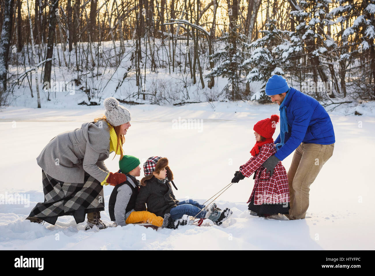 Famiglia giocare nella neve con una slitta Foto Stock