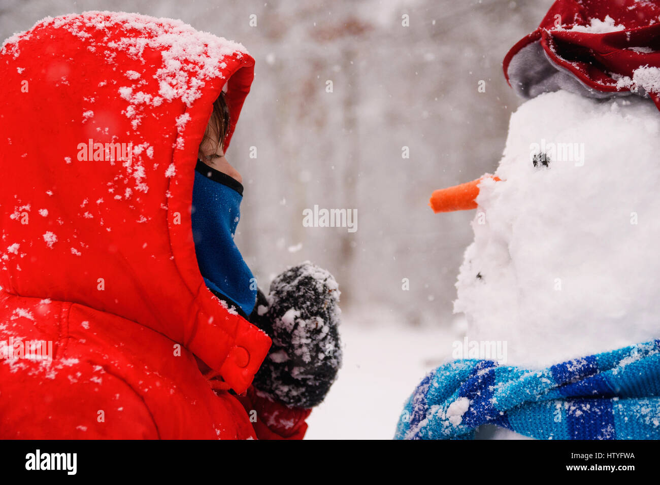 Ragazza in piedi di fronte ad un pupazzo di neve Foto Stock