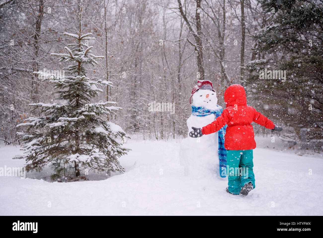 Ragazza in piedi dal pupazzo di neve con le braccia aperte Foto Stock