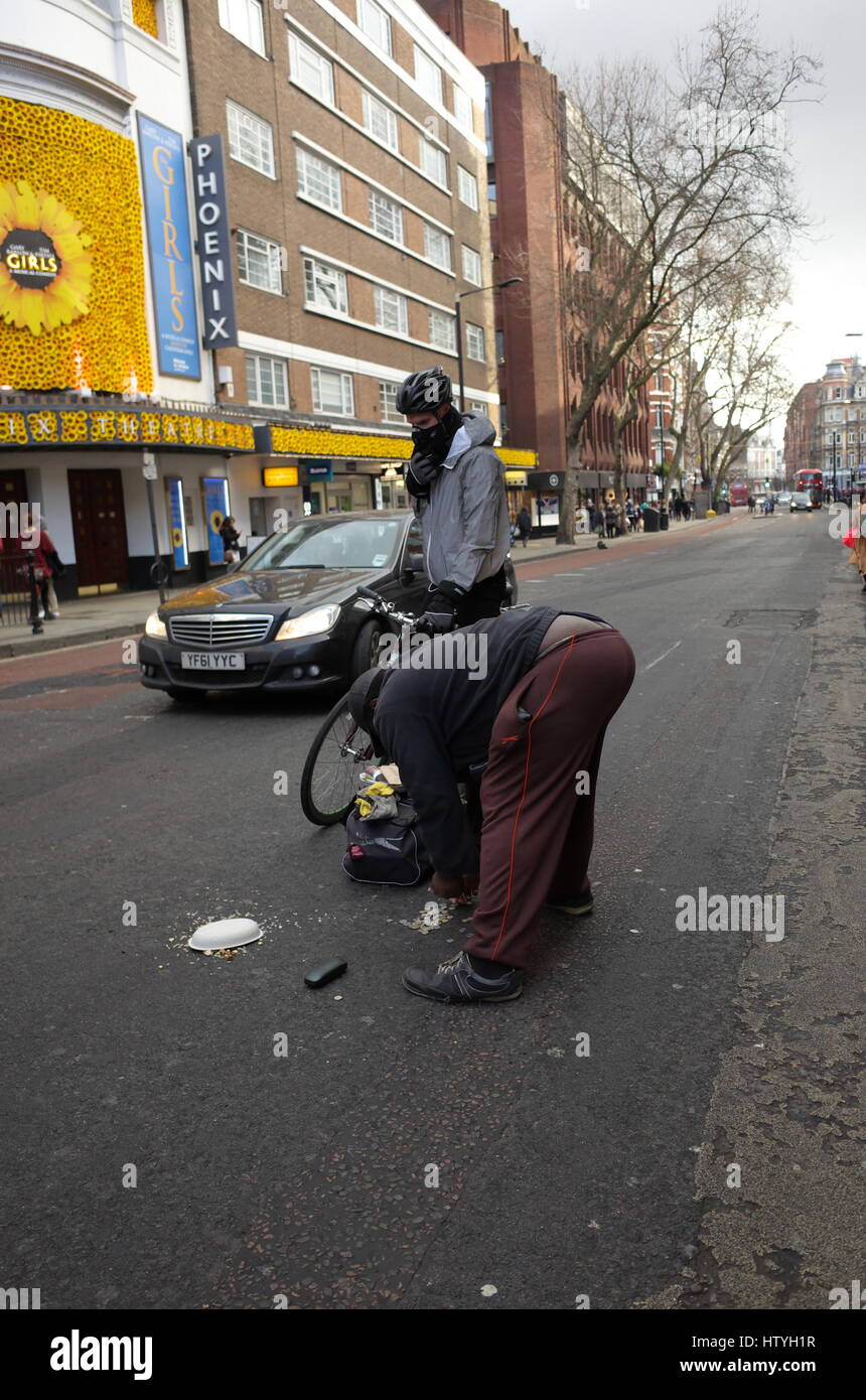 Senzatetto preleva il suo denaro dalla strada dopo essere stato in una collisione con un ciclista a Londra in Inghilterra Foto Stock