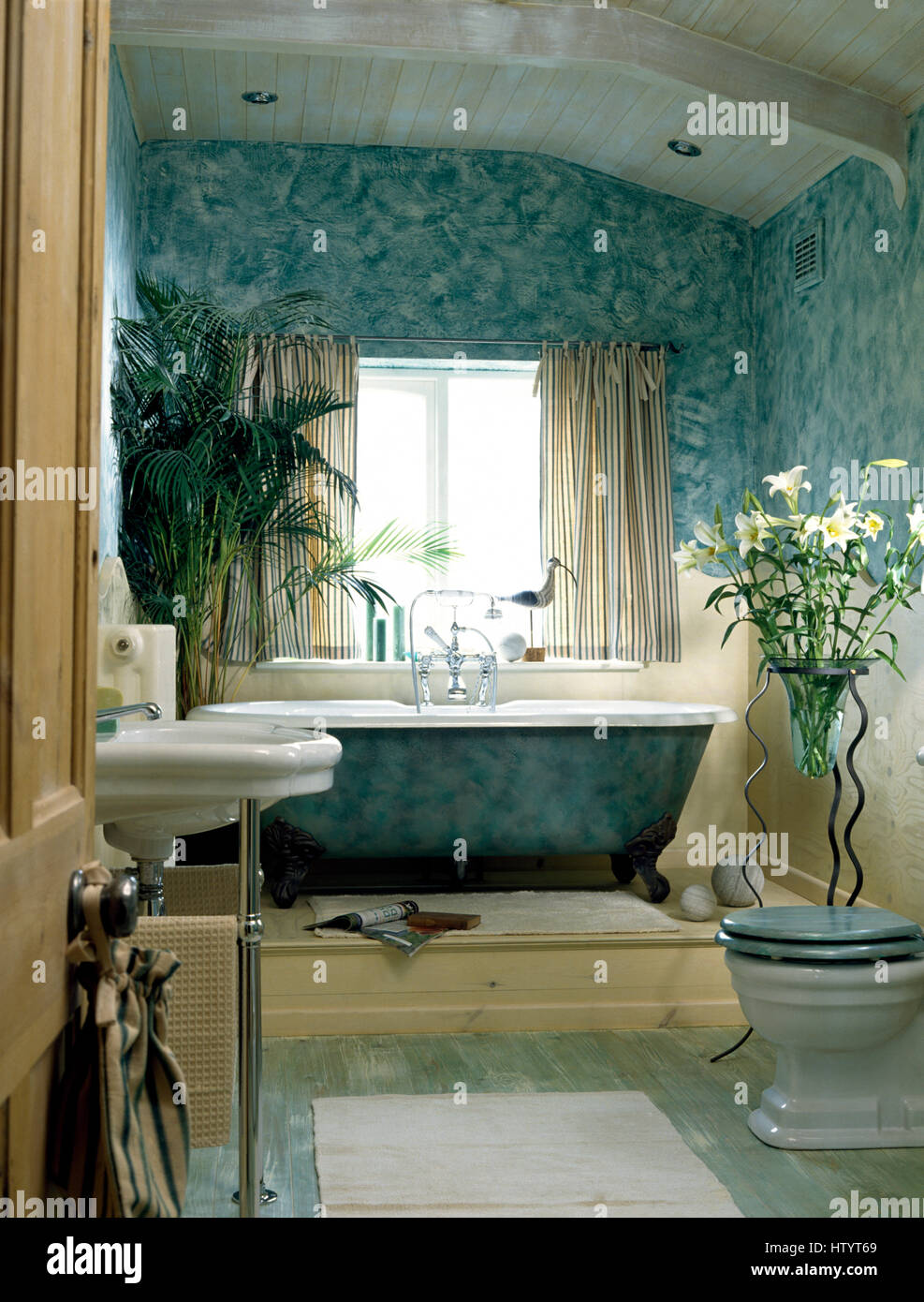 Roll top bagno su una piattaforma bassa in un bagno con decorativamente pareti dipinte Foto Stock