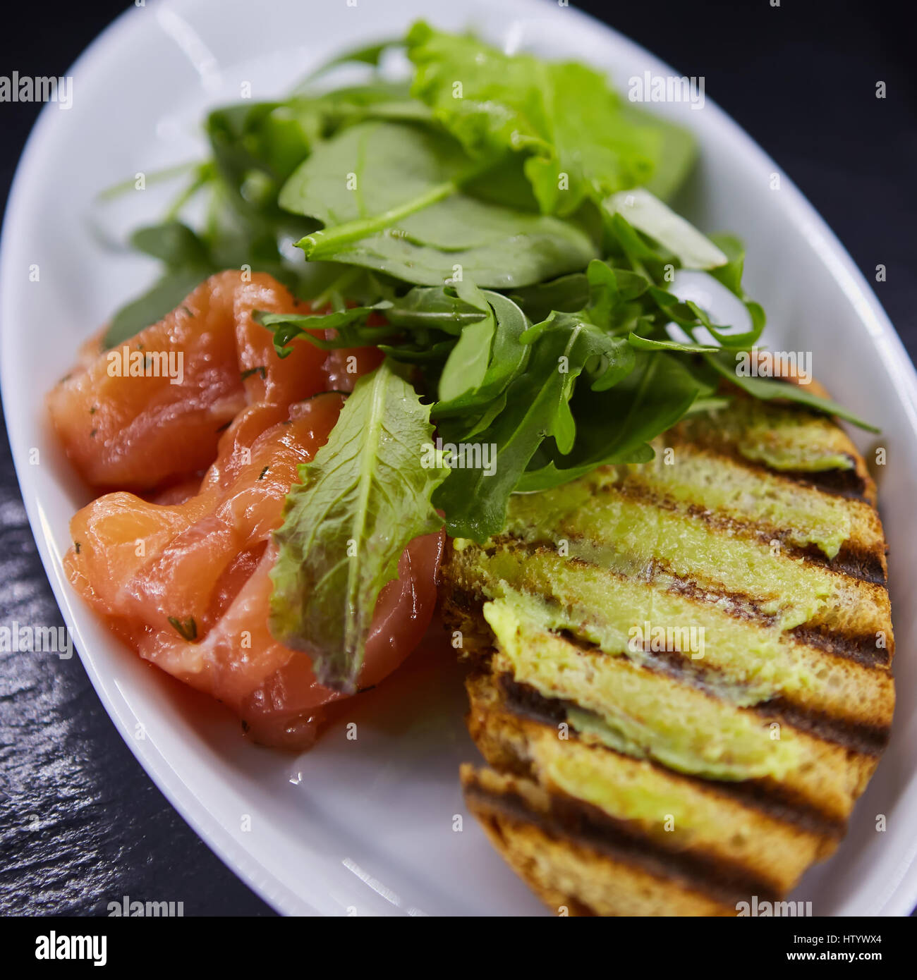 Panino con salmone affumicato, formaggio, i pomodori e le erbe per una sana prima colazione. close up Foto Stock