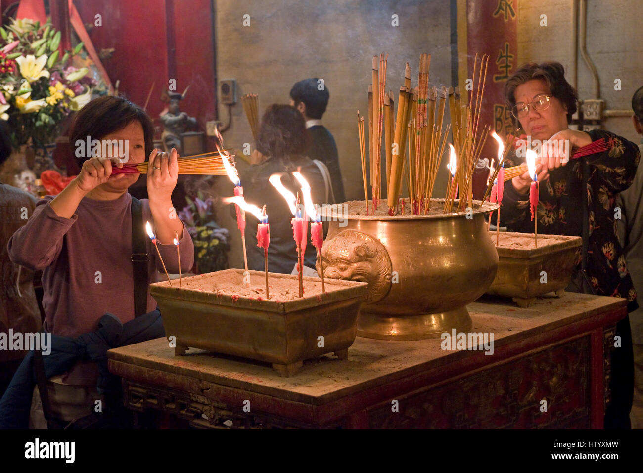 La popolazione locale presso il Tempio di Man Mo in Hong Kong illuminazione bastoncini di incenso prima di preghiera con candele bruciato. Foto Stock