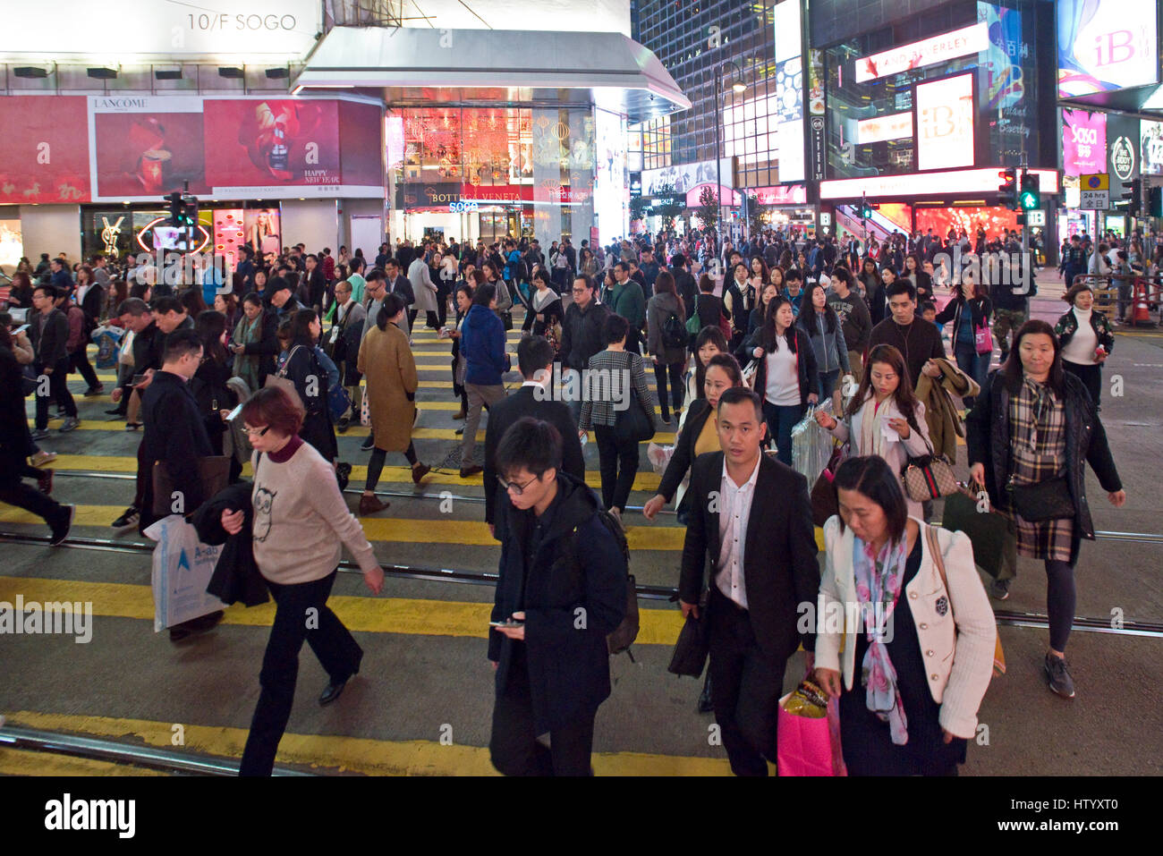 Un occupato trafficato incrocio in Causeway Bay, Hong Kong, per i pedoni che attraversano la strada con alcuni motion blur. Foto Stock