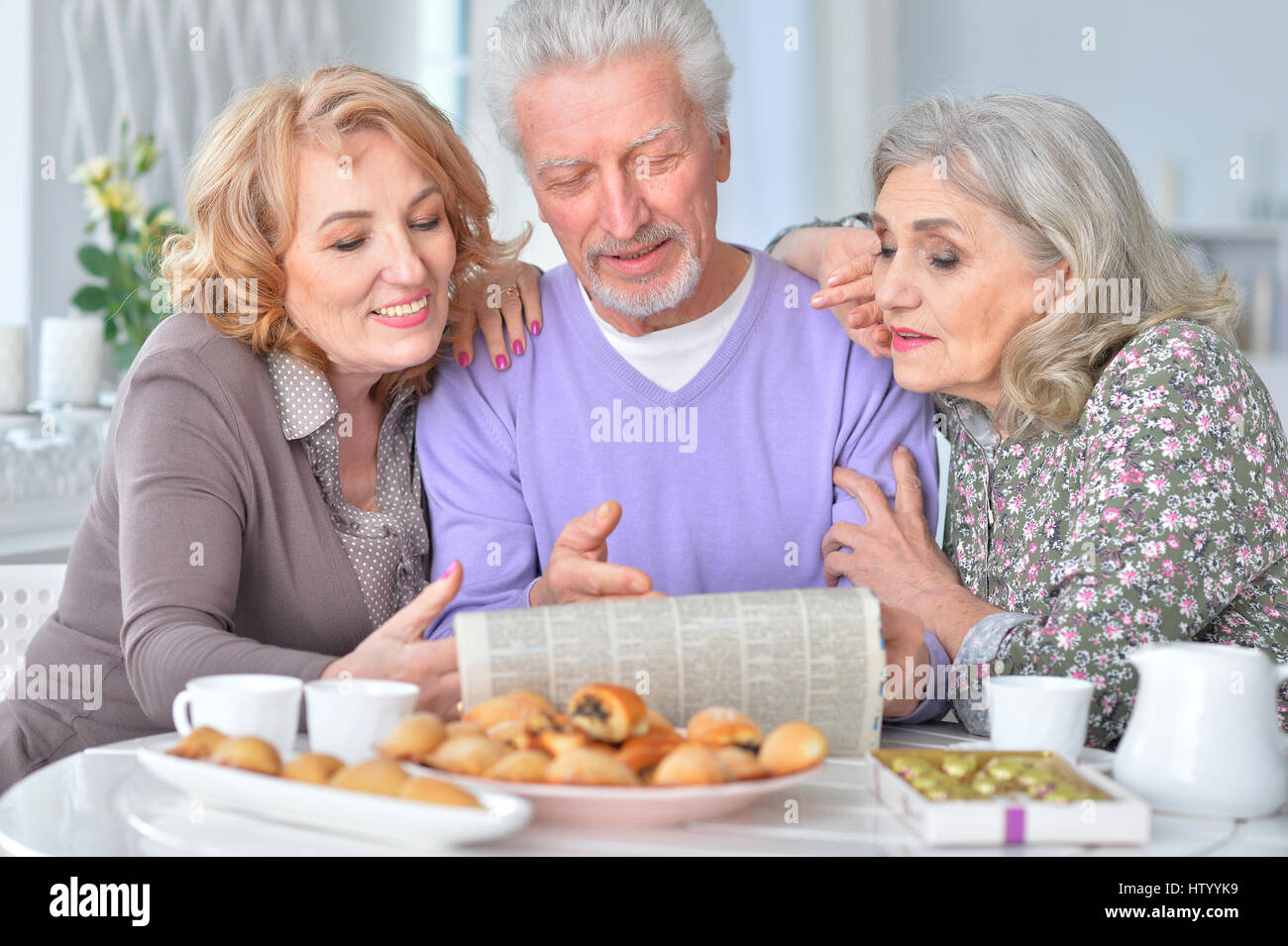 Le persone anziane aventi la prima colazione e la lettura di un quotidiano Foto Stock