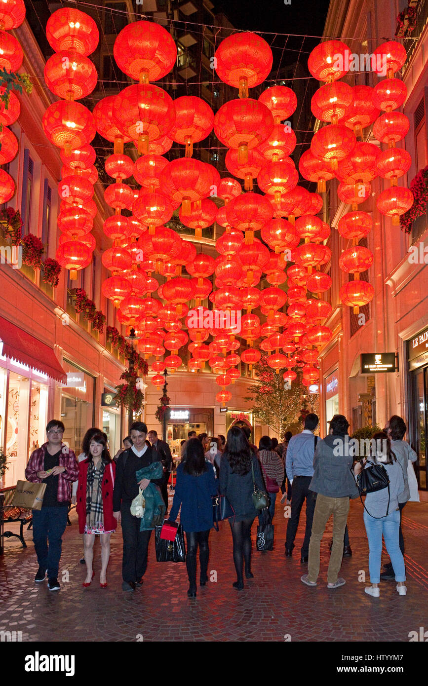 La popolazione locale e i turisti a piedi lungo una strada di Hong Kong con i tradizionali lanterne cinesi decorazioni di riagganciare per celebrare il nuovo anno. Foto Stock