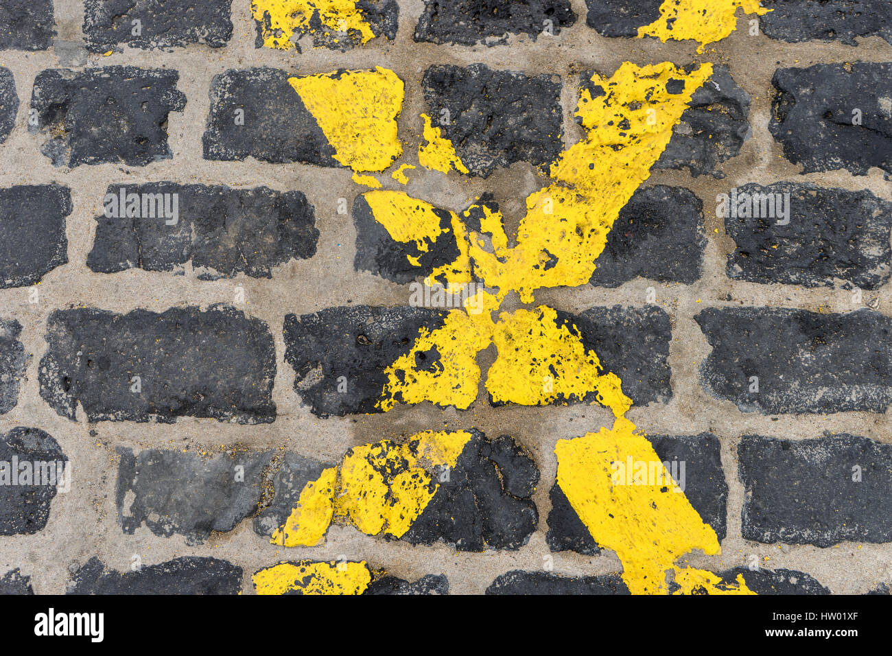 Croce di colore giallo su nero pietre per pavimentazione Foto Stock