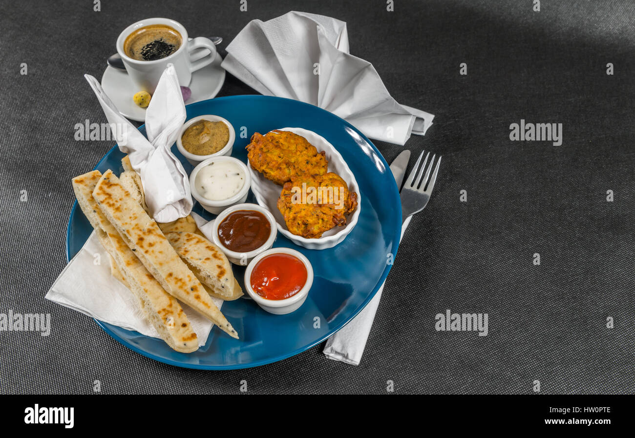 Indiano orientale set, pane naan e onion bhaji, quattro salse, blue plate, caffè nero, gustoso impostato Foto Stock