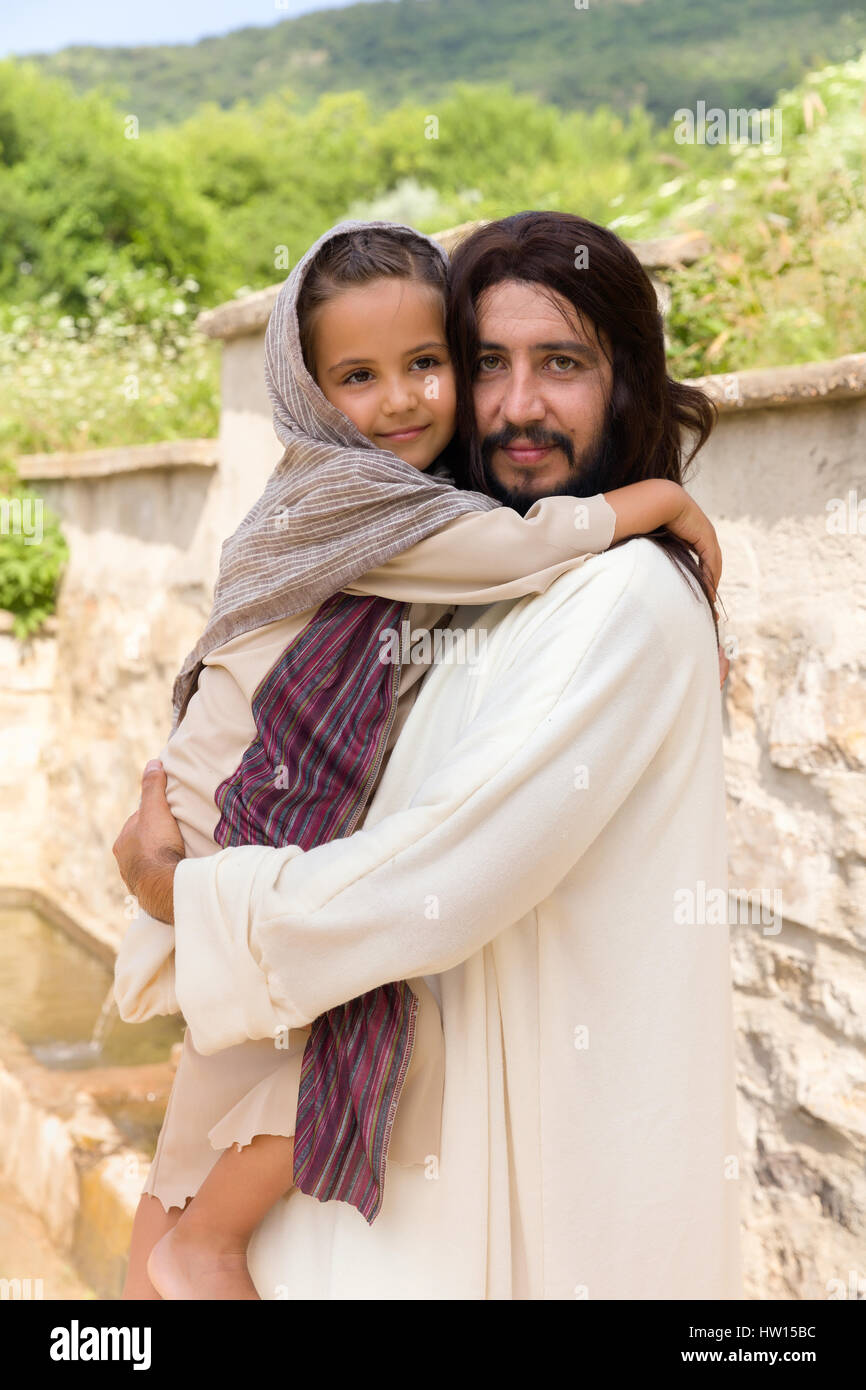Scena biblica quando Gesù dice, lasciate che i bambini vengano a me, la benedizione di una bambina. La rievocazione storica di un antico pozzo di acqua. Foto Stock