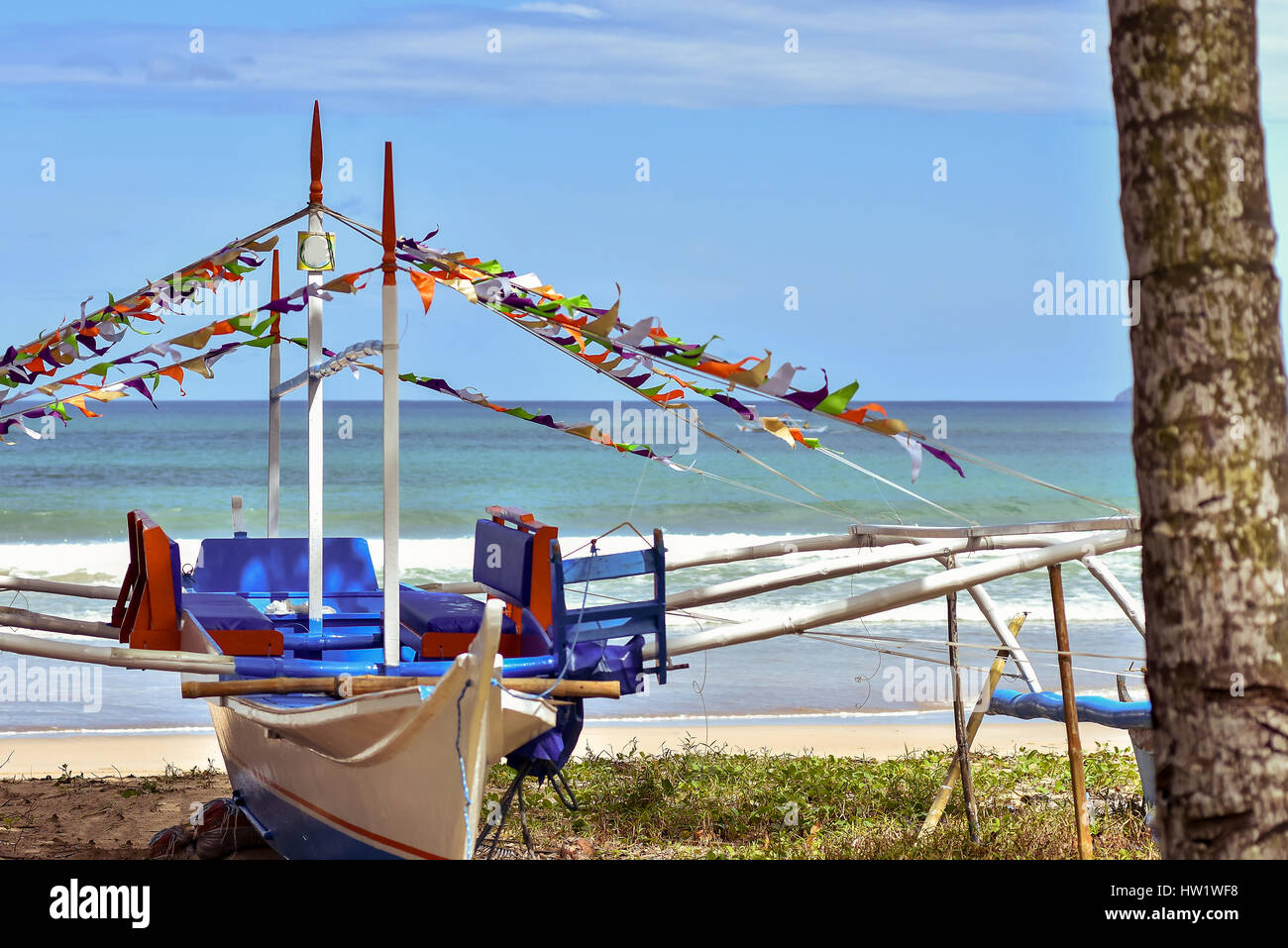 Tradizionale pompa filippino barca con out riggers e posti a sedere fino a terra su breezy day con la spiaggia, il mare e il cielo dello sfondo. Foto Stock