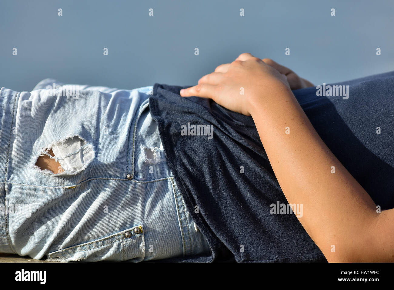 Una giovane donna della metà del corpo rilassante stabiliscono crogiolandovi sotto i raggi del sole al tramonto vicino ora d'oro. Foto Stock