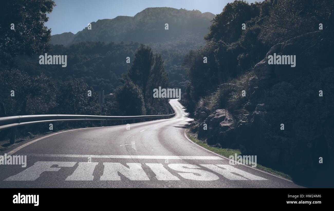 Lunga strada deserta attraverso le montagne con la parola fine su asfalto Foto Stock