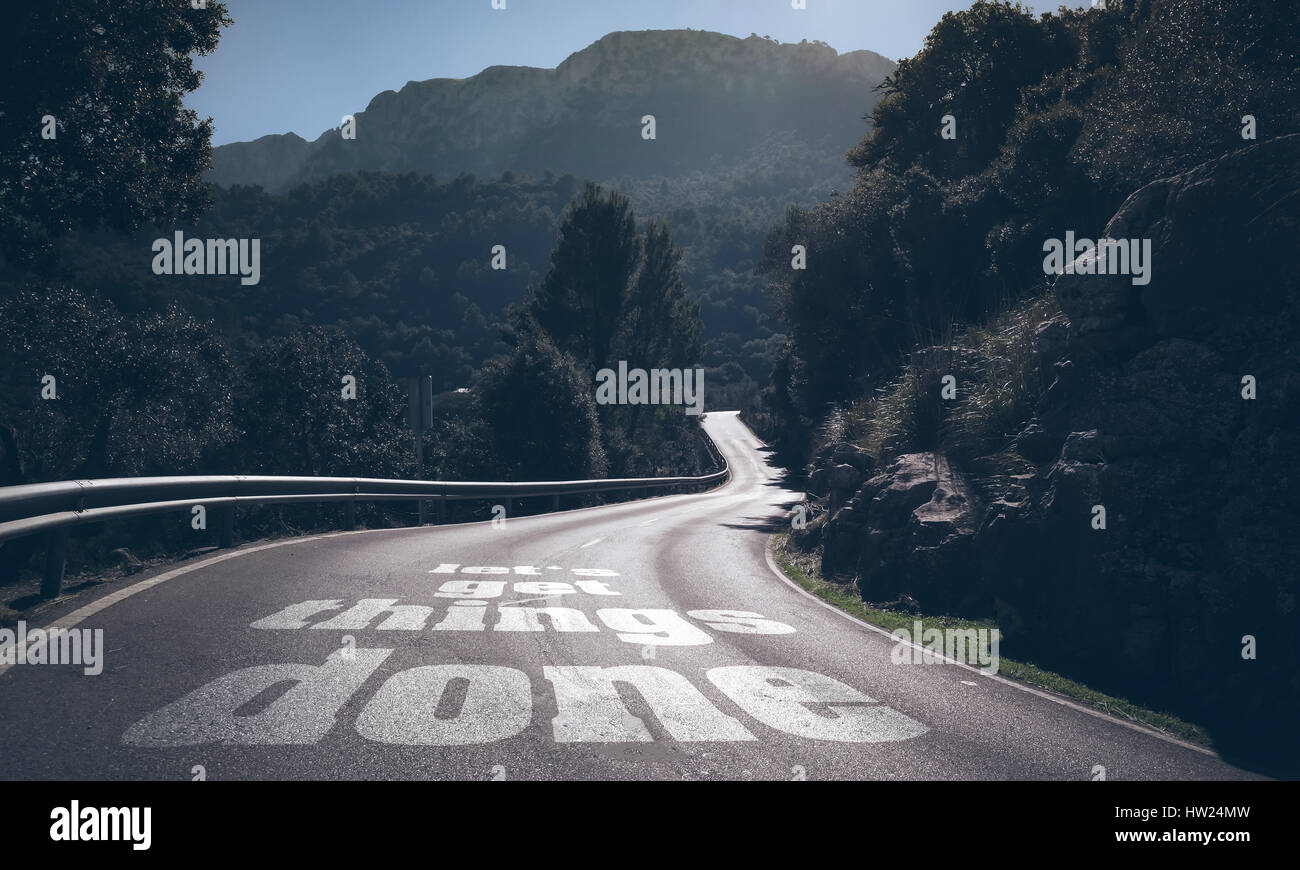 Lunga strada deserta attraverso le montagne con parole consente di ottenere le cose fatte scritto su asfalto Foto Stock