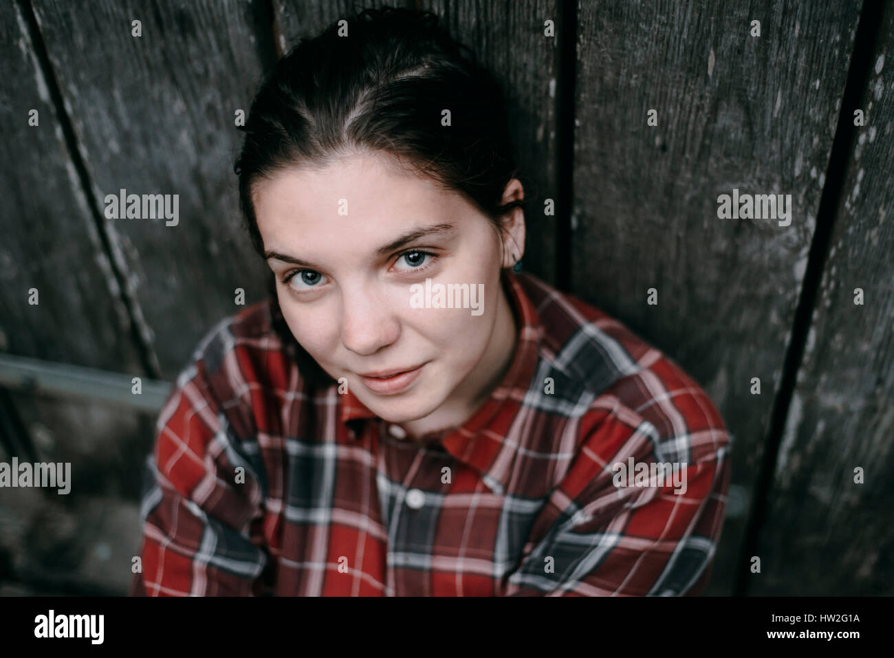 Sorridente donna caucasica appoggiata sulla porta di legno Foto Stock