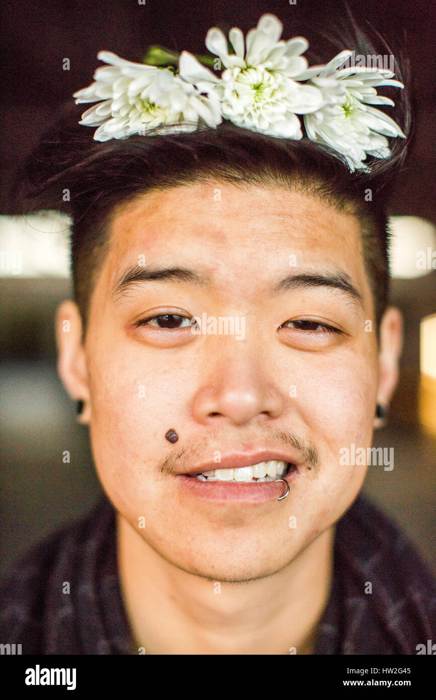 Ritratto di androgino uomo asiatico con i fiori nei capelli Foto Stock