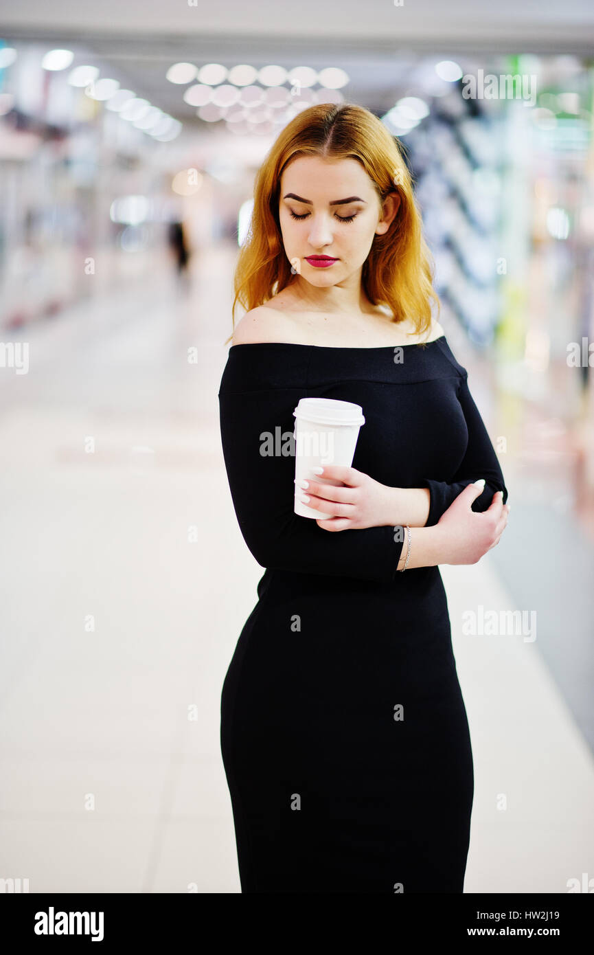 Moda Capelli rossi ragazza indossare il vestito nero con luminosi rendono  tenendo una tazzina di caffè Commercio al centro commerciale. Foto di stile  dai toni Instagram filtri Foto stock - Alamy