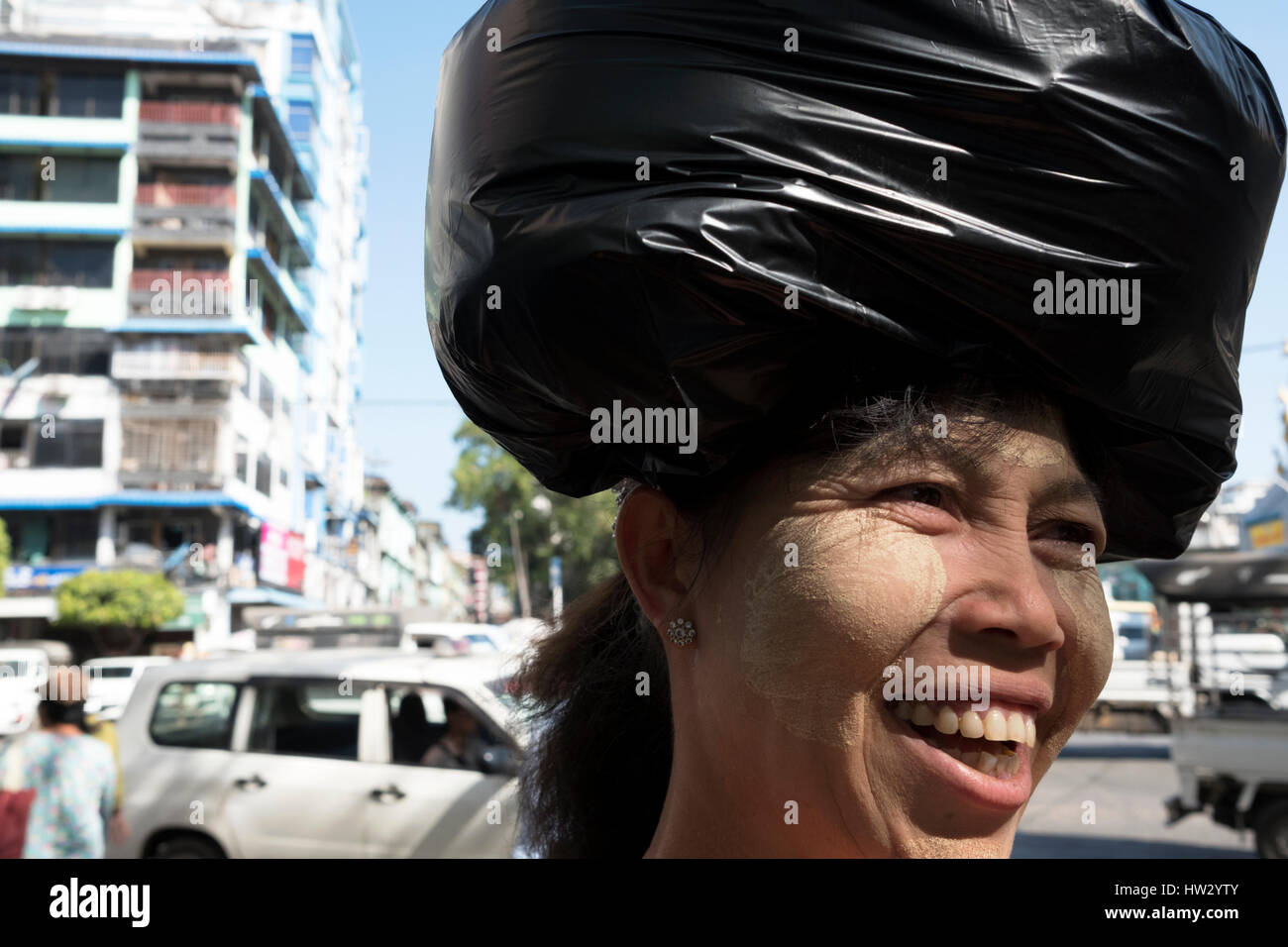 Una donna birmano indossando crema per il viso, porta un sacchetto di plastica sul suo capo in Sule Pagoda Road, Yangon, Regione di Yangon, Myanmar Foto Stock