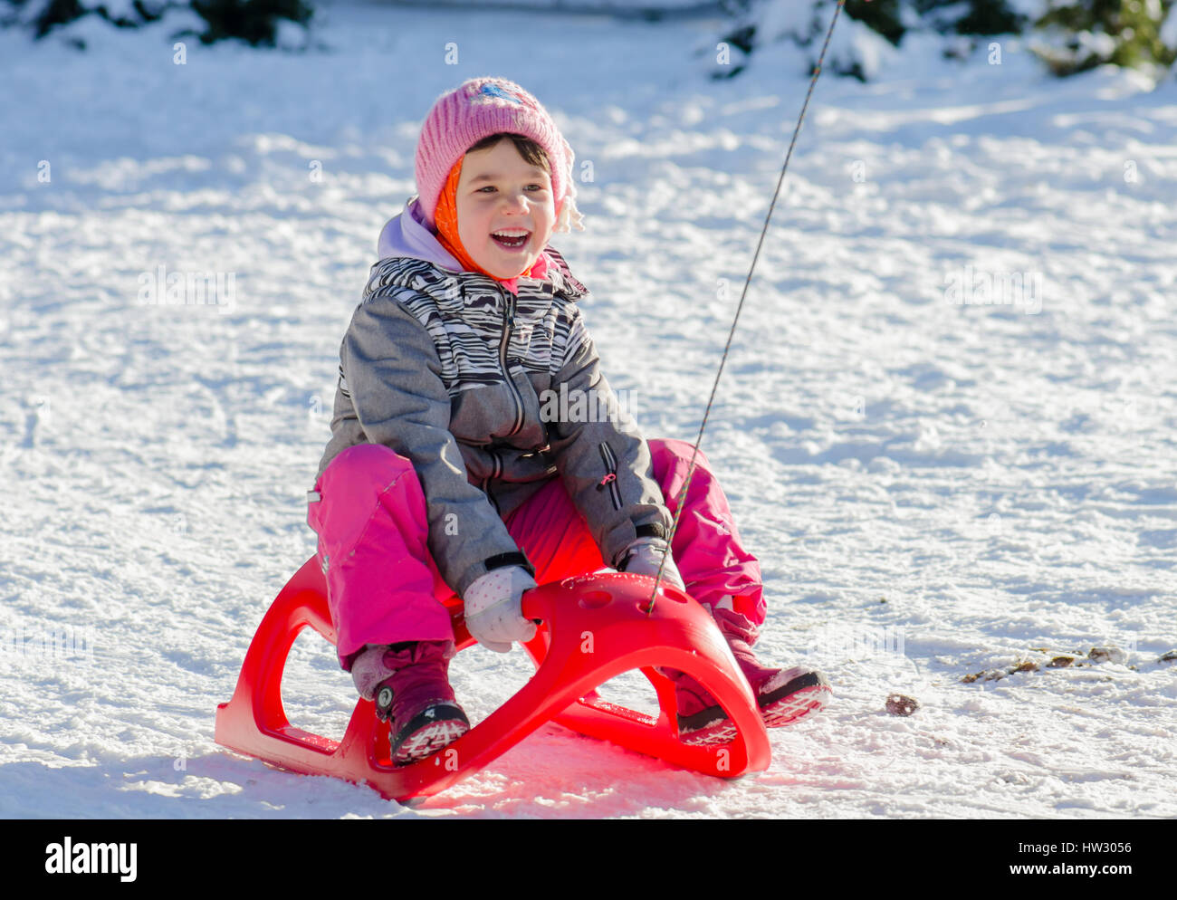 Il Toddler ragazza in tuta invernale in slittino divertirsi con la neve Foto Stock