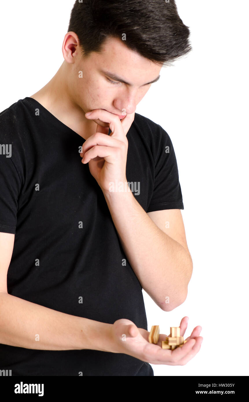 Adolescente uomo concentrata pensare come risolvere un bamboozler 3D Seghetto isolato su sfondo bianco Foto Stock