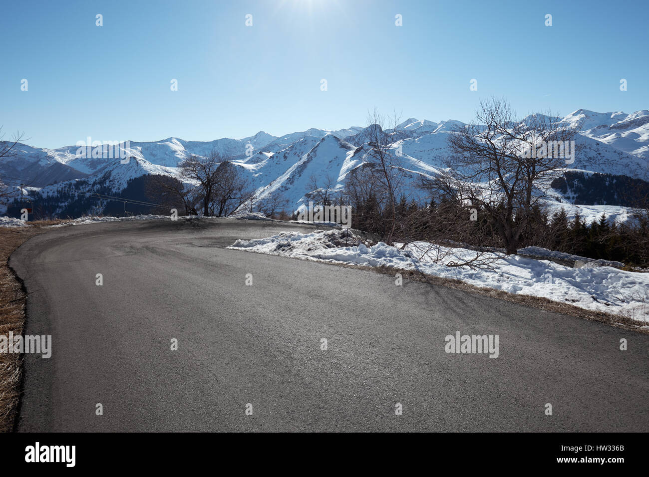 Vuoto su strada di montagna con vista delle Alpi, cielo blu in una giornata di sole Foto Stock