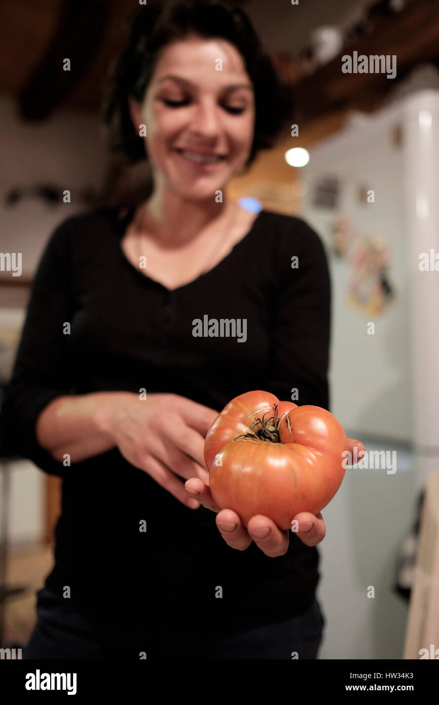 Giovane donna rumena tenendo un cimelio di grandi dimensioni il pomodoro crebbe nel suo giardino in Saschiz, Romania. Foto Stock