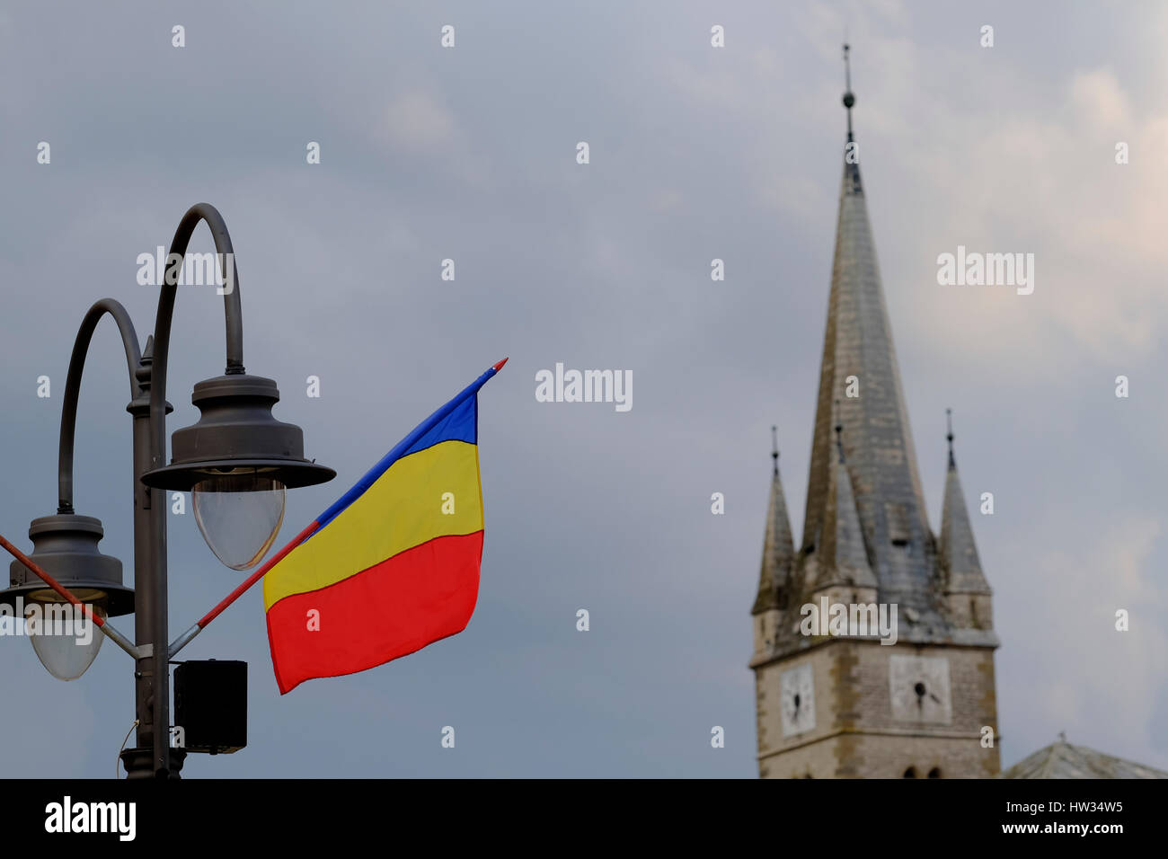 Bandiera rumena e il campanile della chiesa riformata nel centro della città di Turda, nella contea di Cluj, Romania. Foto Stock