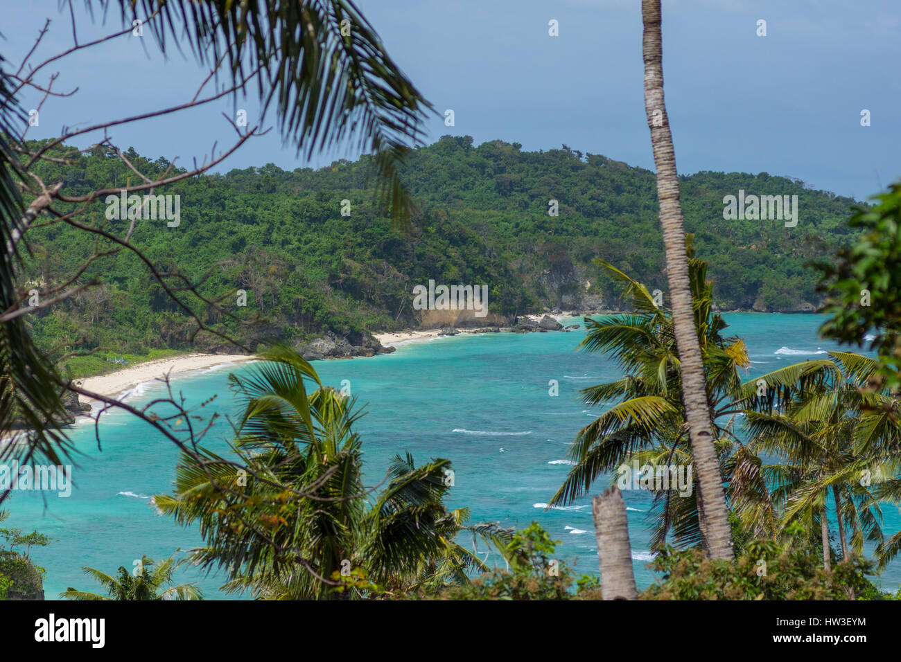 Un idilic vuoto paradiso bella spiaggia di sabbia bianca con calma azzurro mare visto da un angolo alto attraverso gli alberi e cespugli. Foto Stock